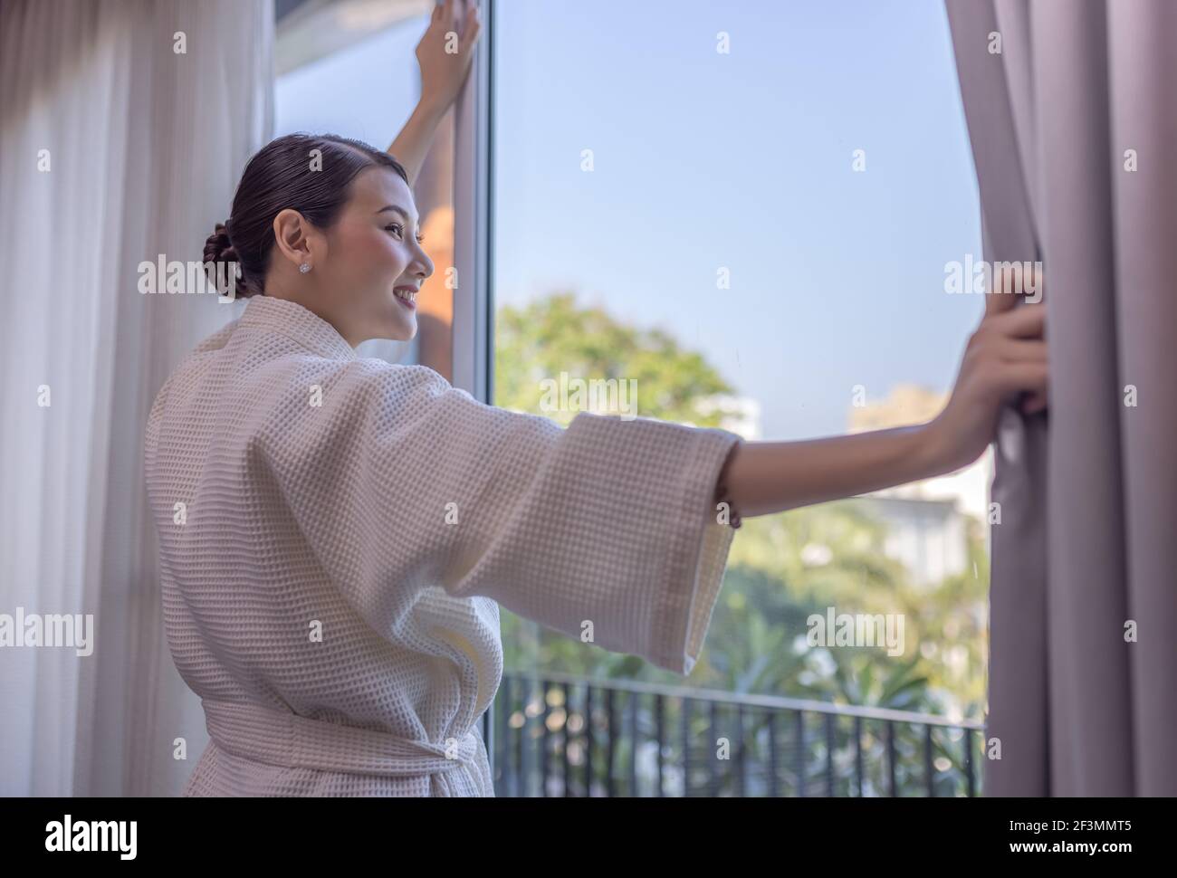 Reisende wunderschöne asiatische Frau lächelt, um über den Aufenthalt zu schauen In der Nähe der Tür im Hotelzimmer Stockfoto