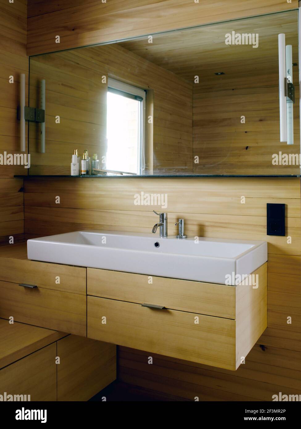 Spiegel über dem Waschbecken im Badezimmer mit Holzvertäfelung in österreichischem Zuhause