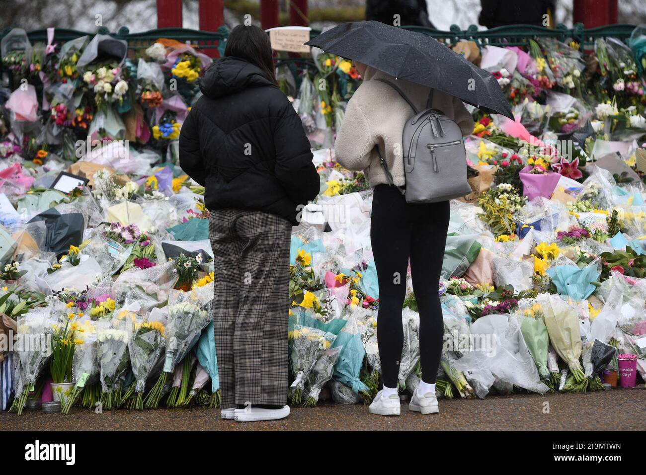 Frauen schauen sich Blumengebete an, die neben dem Bandstand in Clapham Common, London, für Sarah Everard hinterlassen wurden. PC Wayne Couzens, 48, erschien im Old Bailey in London und wurde wegen der Entführung und Ermordung des 33-Jährigen angeklagt. Bilddatum: Dienstag, 16. März 2021. Stockfoto