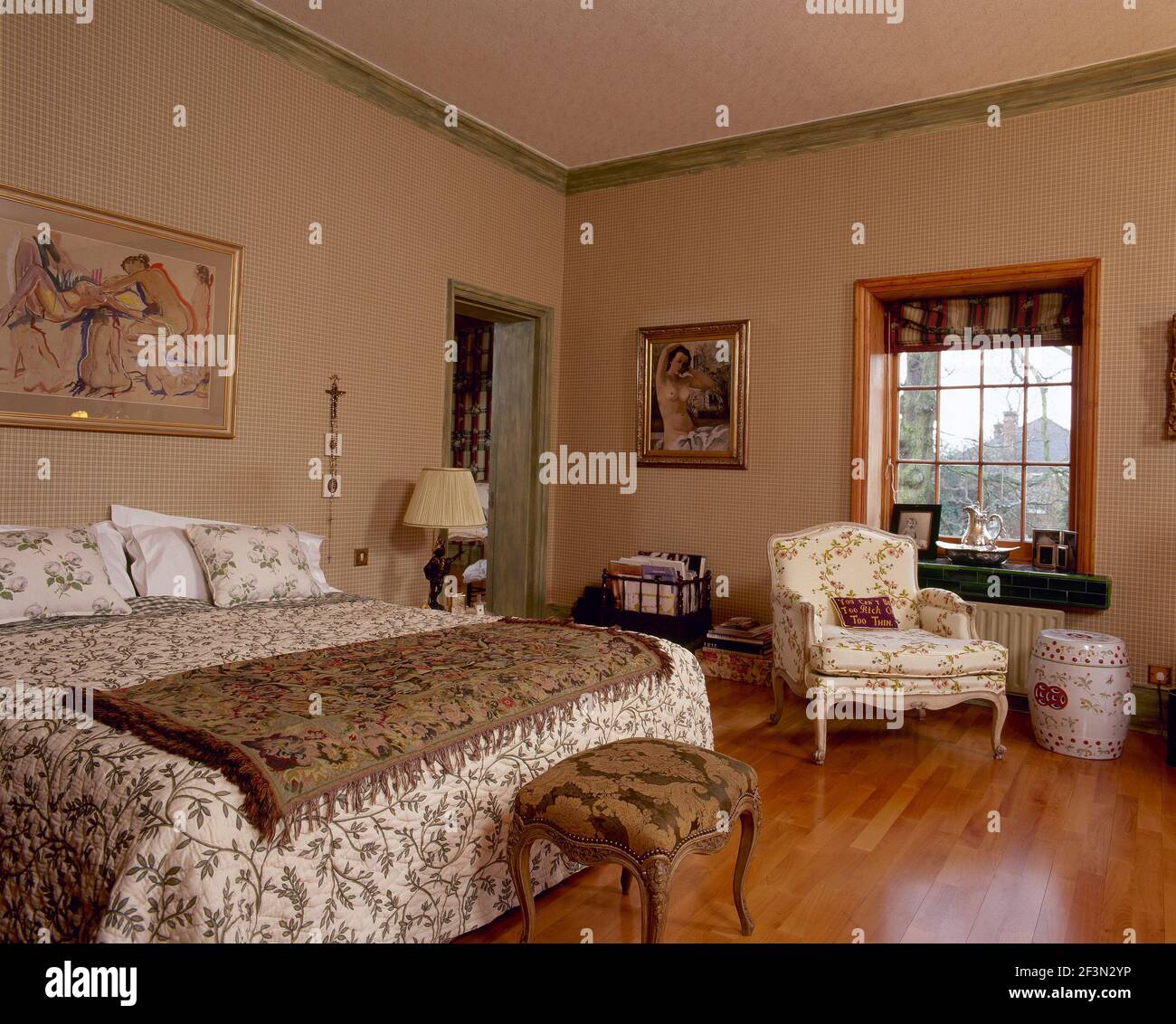 Traditionelles goldfarbenes Schlafzimmer mit floralen Möbeln und Polstermöbeln. Stockfoto