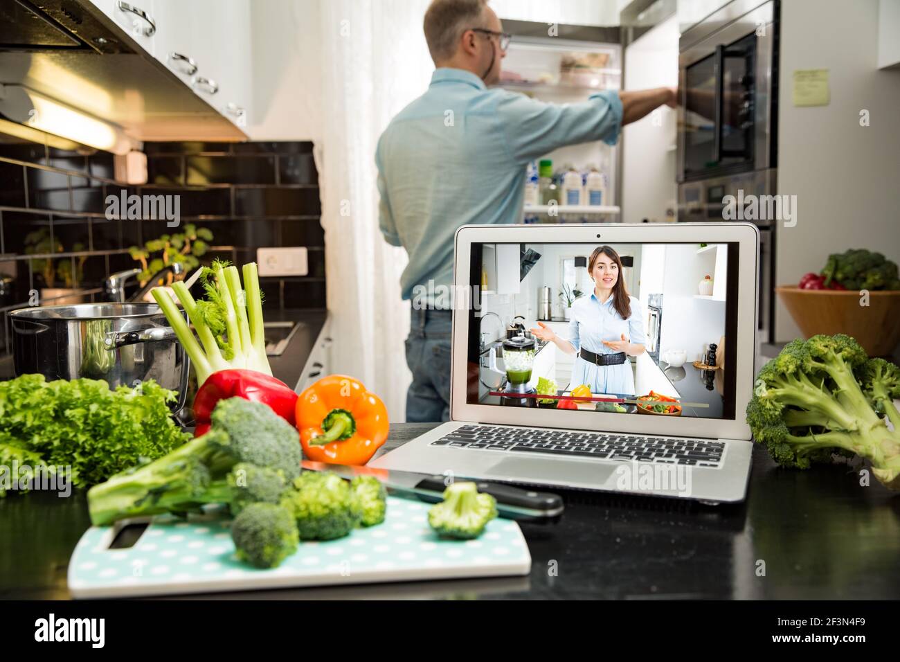 Schöne glückliche Frau Streaming Broadcast Video Blog über leckere und gesunde Lebensmittel aus der Küche zu Hause. Gesunder Lebensstil und soziale Medien. Mann beobachtet Stockfoto