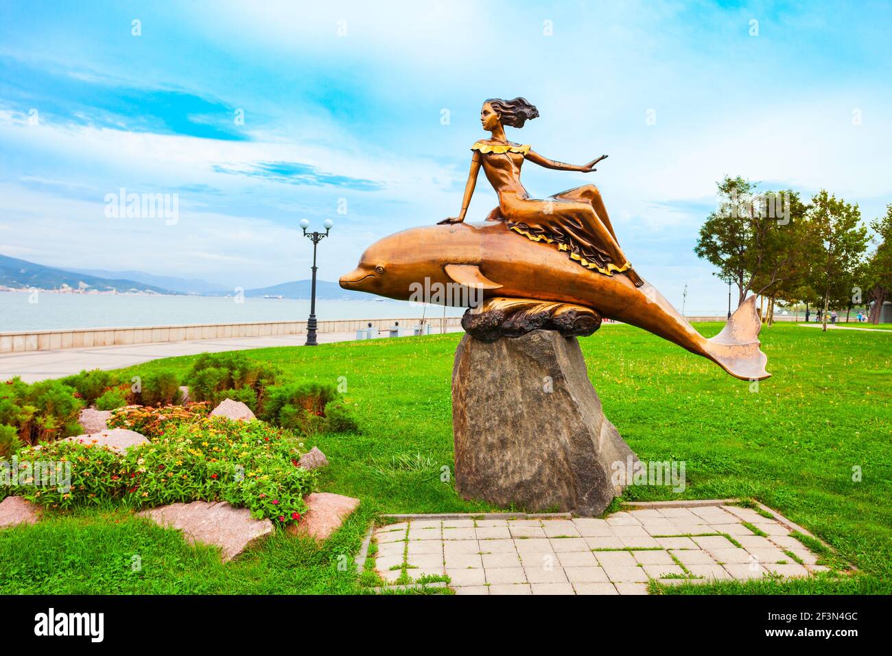 Noworossijsk, Russland - 02. Oktober 2020: Mädchen auf einer Delphin-Skulptur in Noworossijsk Stadt. Noworossijsk ist der Haupthafen am Schwarzen Meer in Krasnodar Stockfoto