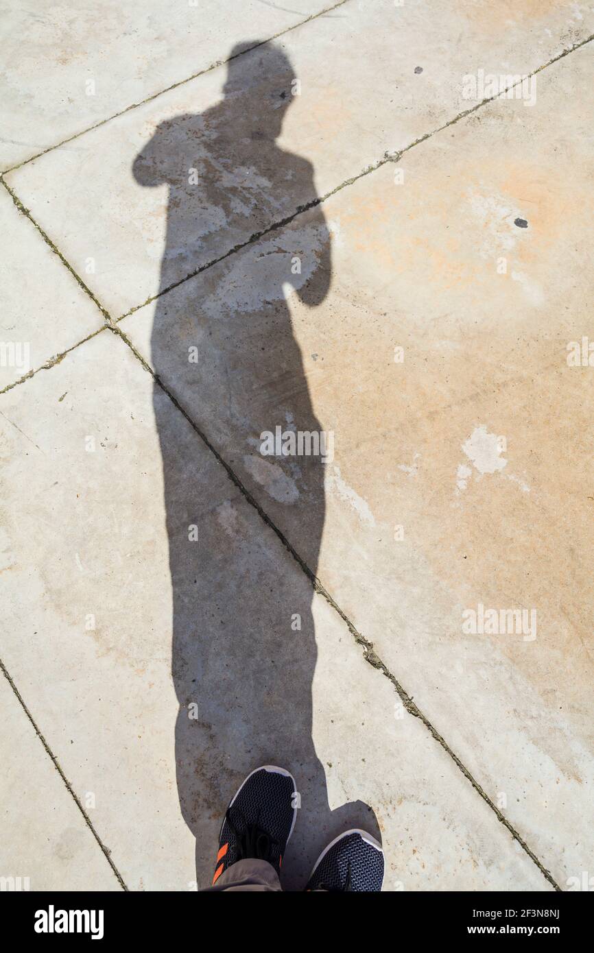 Ein Kind, das ein Foto von ihrem Schatten gegen die Gepflasterter Boden Stockfoto