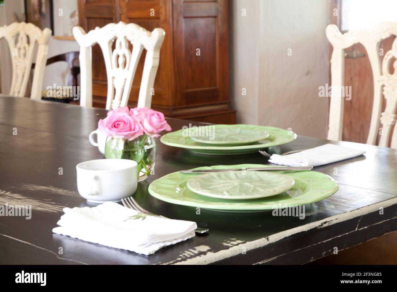 Tisch mit grünen Krokerei, Vase mit rosa Rosen und weißen Tassen gelegt Stockfoto