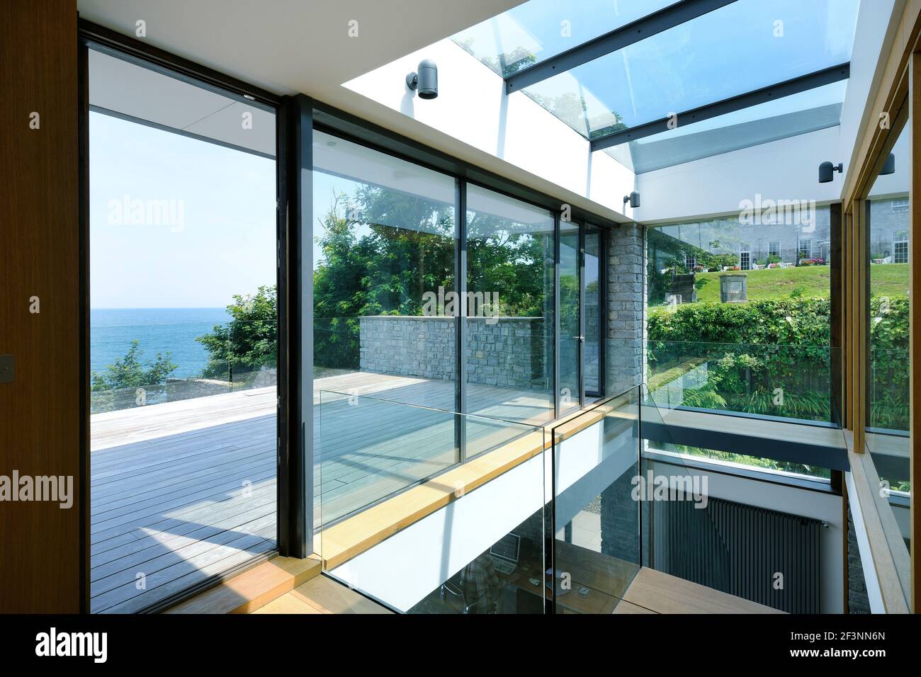 Das Innere eines modernen Hauses an der Küste. Große Glasschiebetüren öffnen sich. Raumhohe Glaspaneele. Ein flaches Gebäude in einer Lage am Meer Stockfoto