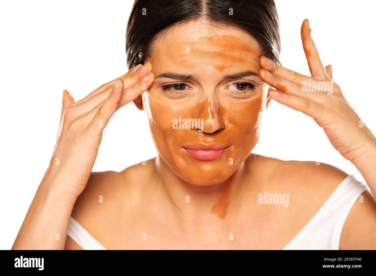 Junge nervöse Frau, die zu dunkle flüssige Grundlage auf sie anwendet Gesicht Stockfoto