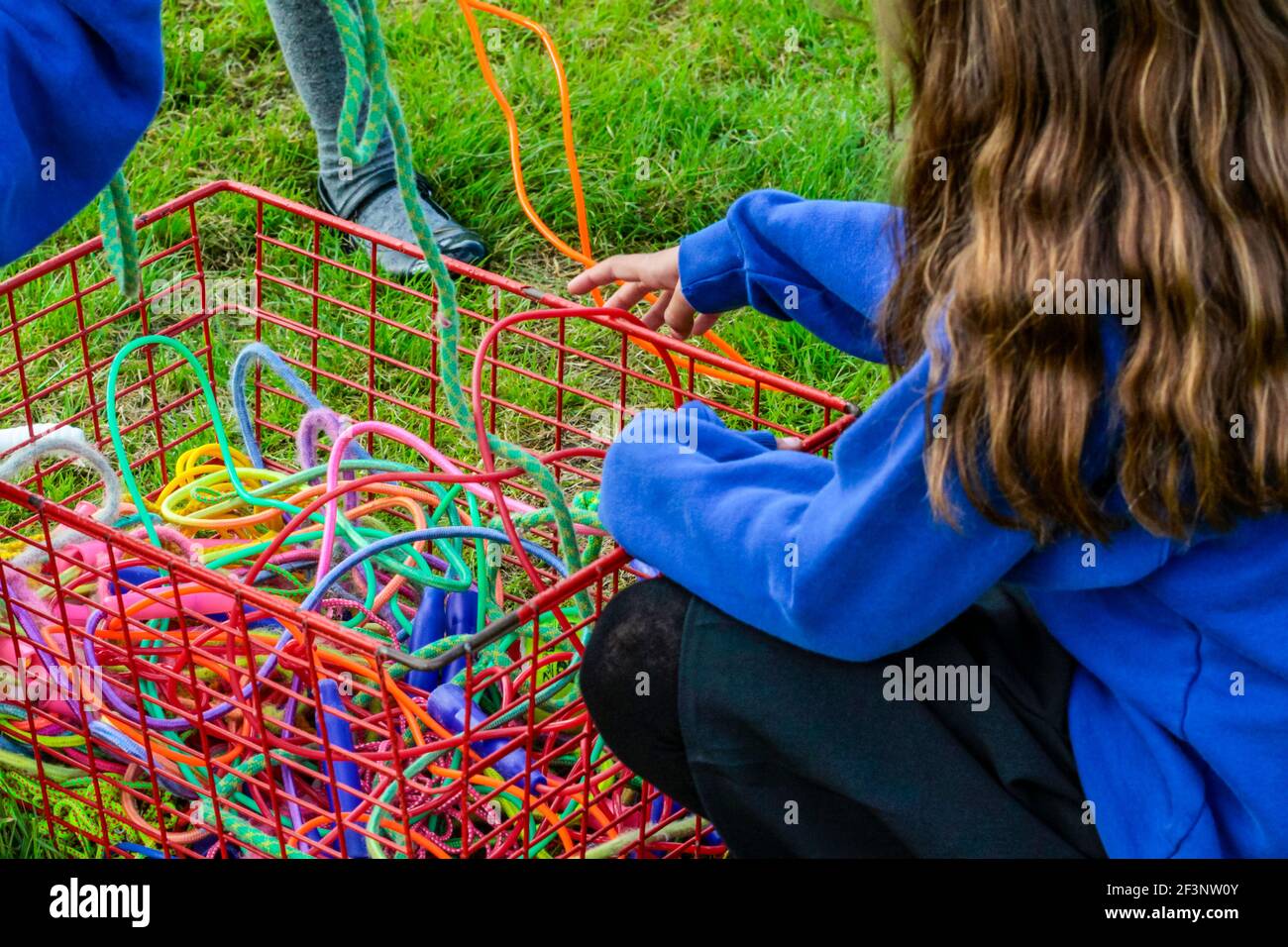 Zwei Schulkinder mit einem Korb aus Springseilen werden nach einer Pause vom Unterricht wieder in die Schule gebracht. Stockfoto