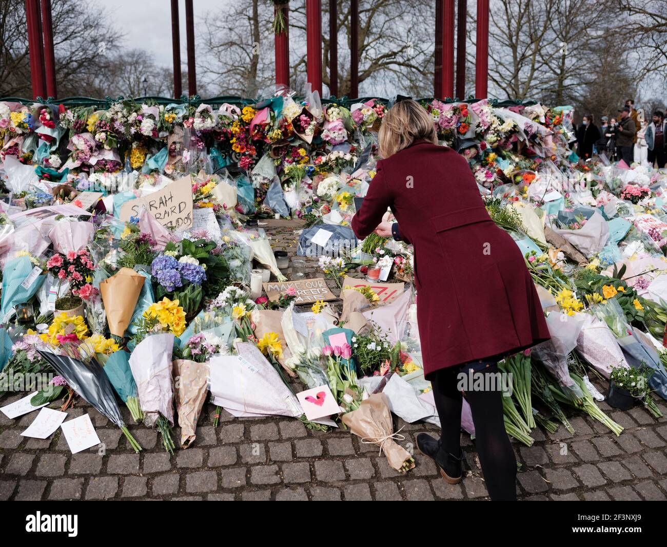 Ein Trauerling stellt Blumen und zündet Kerzen für Sarah Everard am Bandstand in Clapham Common, 14. März 2021 Stockfoto