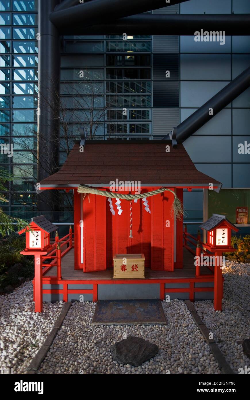 Eine niedrige Weitwinkelansicht zeigt einen kleinen zinnoberfarbenen Shinto-Schrein Außerhalb des NTV Tower im Shiodome Business Complex in der Nähe Shimbashi District Stockfoto