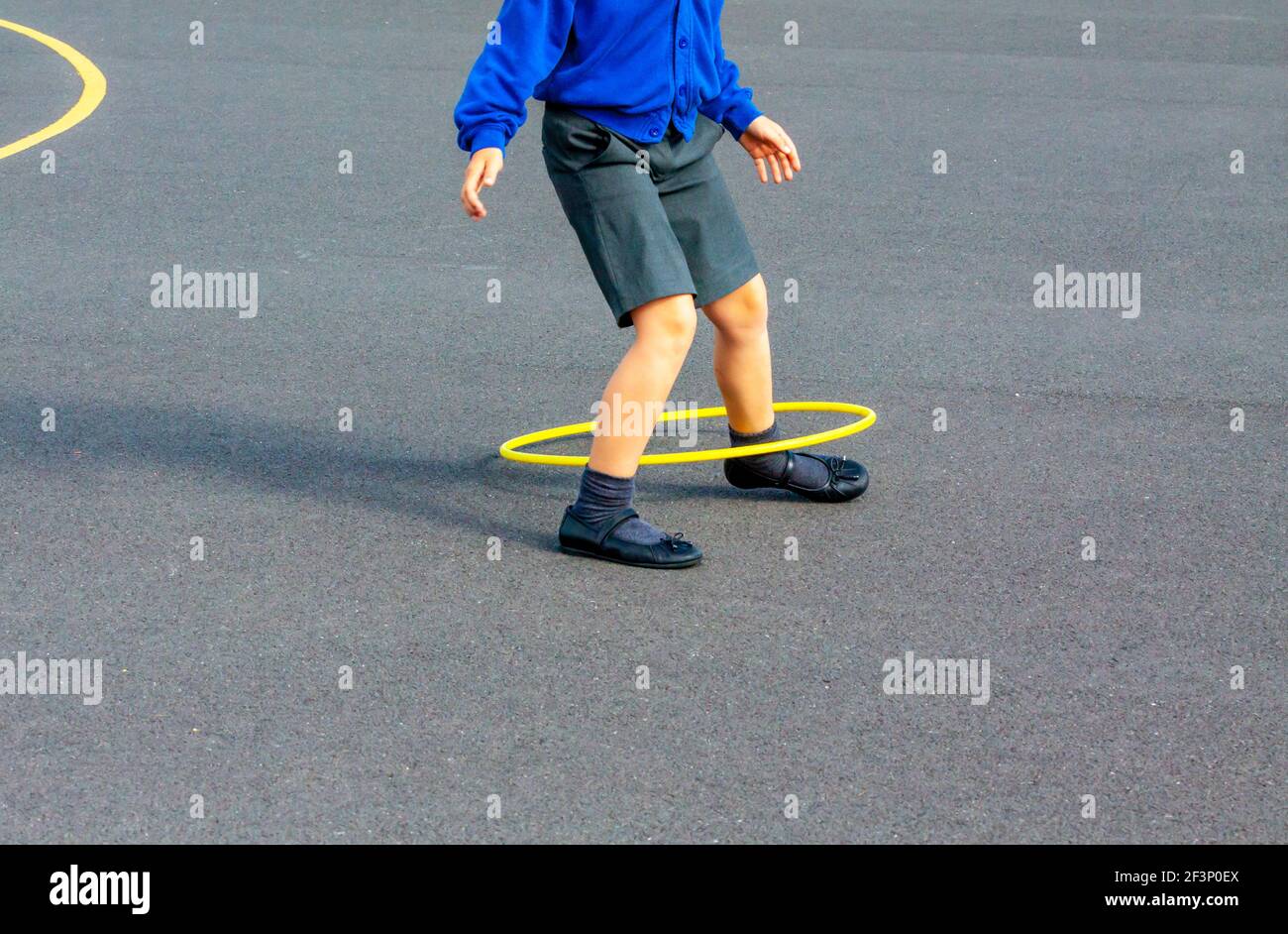 Grundschulkind spielt mit einem Reifen draußen auf einem Schulhof während einer Pause vom Unterricht. Stockfoto