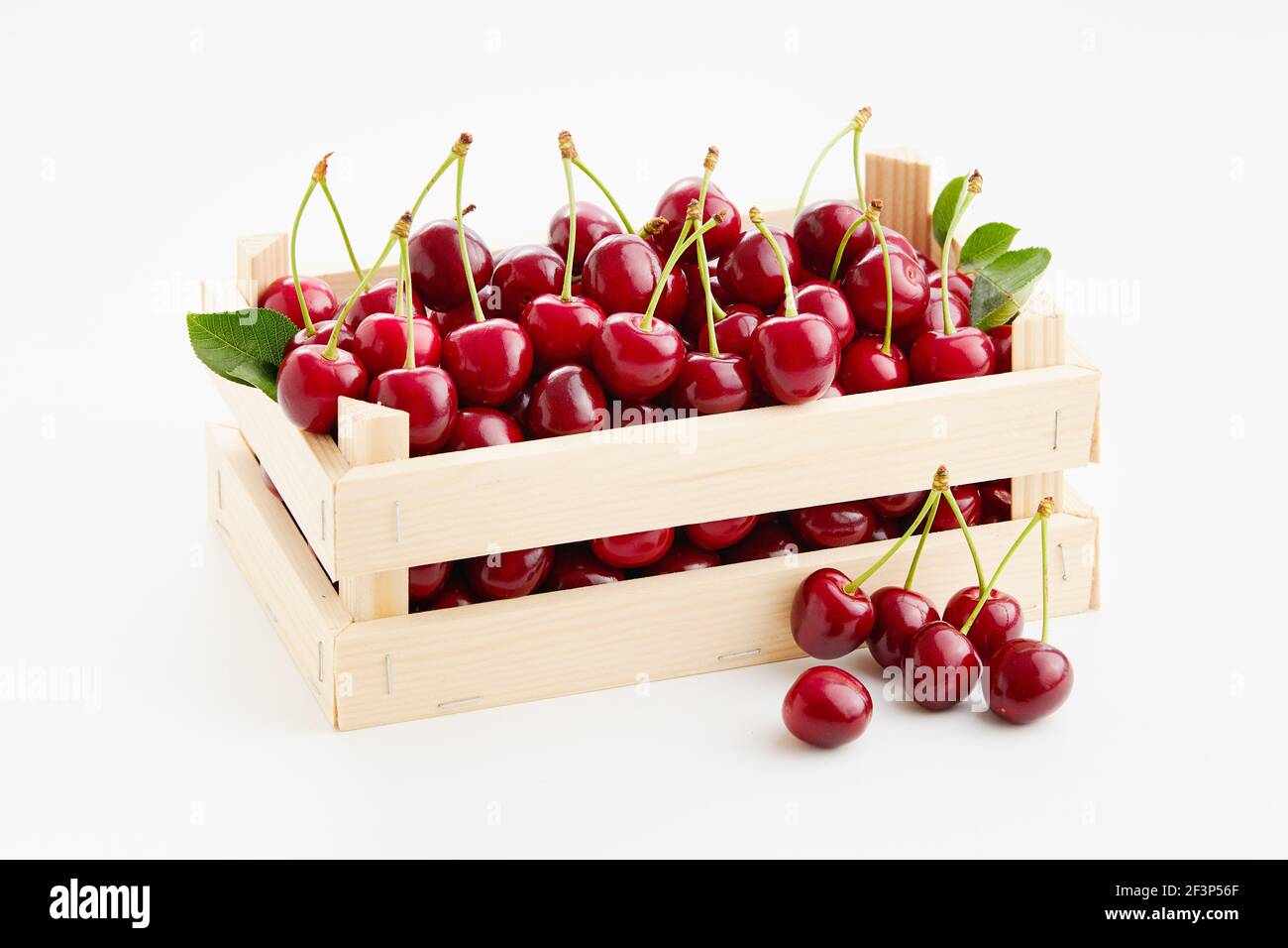 Frische, reife Süßkirschen in kleiner Holzkiste auf weißem Hintergrund. Stockfoto