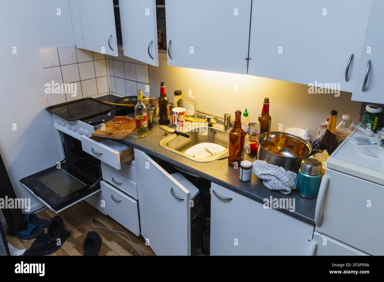 Chaotische Küche nach der Party. Bierflaschen, Teller in einem Waschbecken, Weinflasche Stockfoto