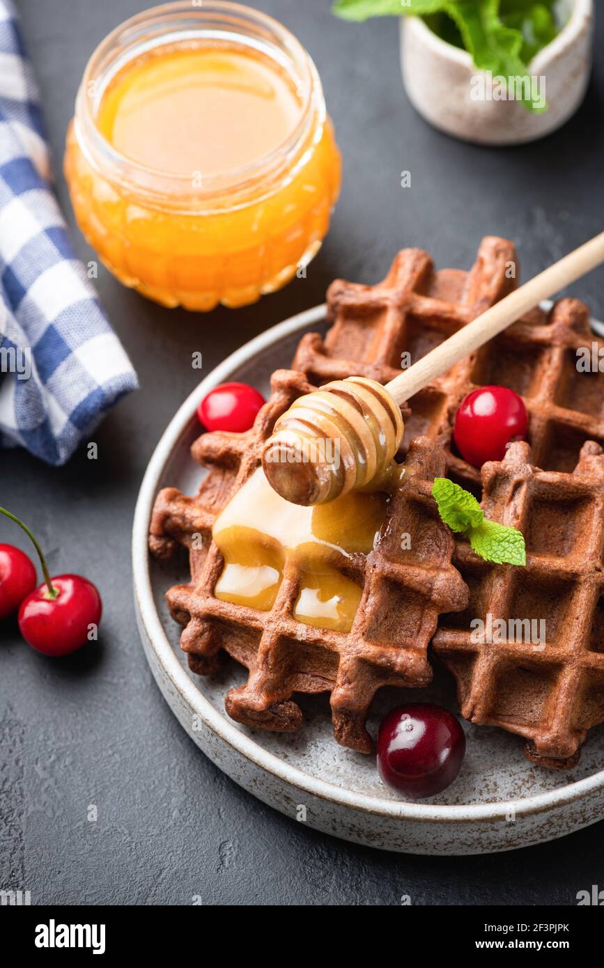 Belgische Schokoladenwaffeln mit Honig und süßer Kirsche. Süßes Dessertessen Stockfoto