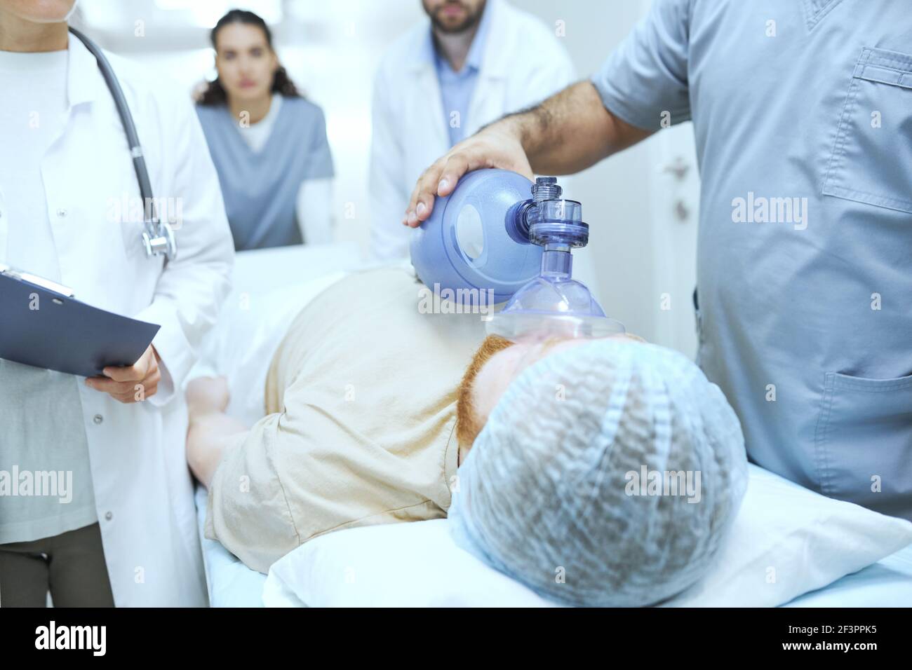 Patient liegt bewusstlos, während Arzt künstliche Beatmung im Krankenhaus Stockfoto