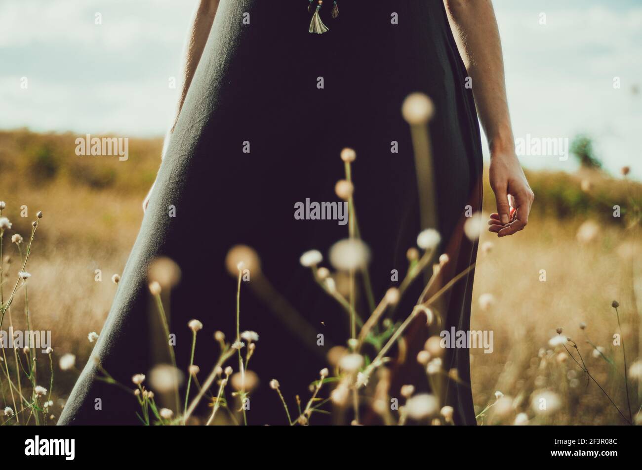 Mittelteil Porträt boho Stil Kleid junge Frau im Gras und Wildblumen mit der Natur verbunden stehen. Konzept: Spiritualität, Zen, Balance Stockfoto