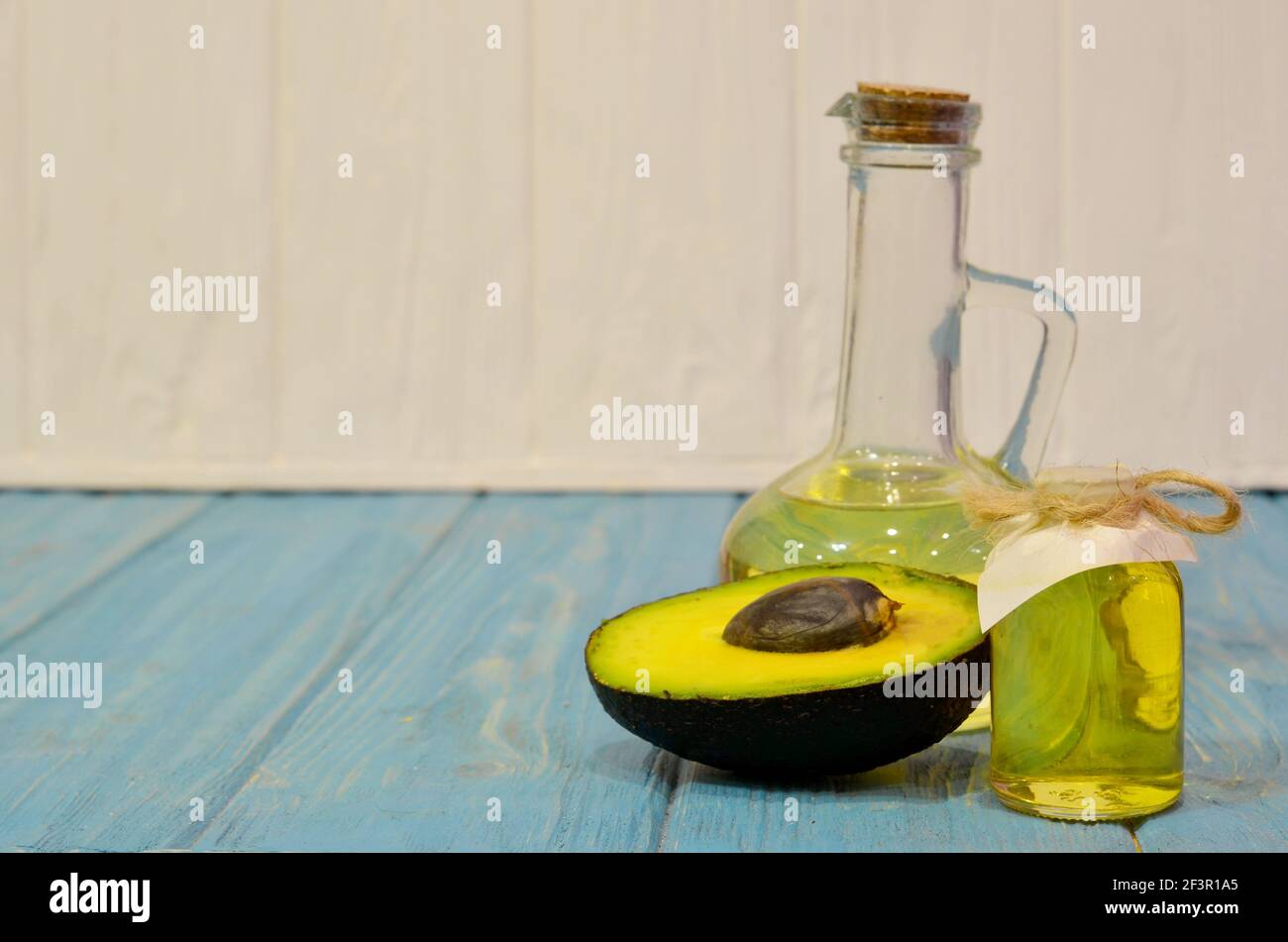 Avocado Öl und halbieren Avocado auf blauem Holz Hintergrund Stockfoto