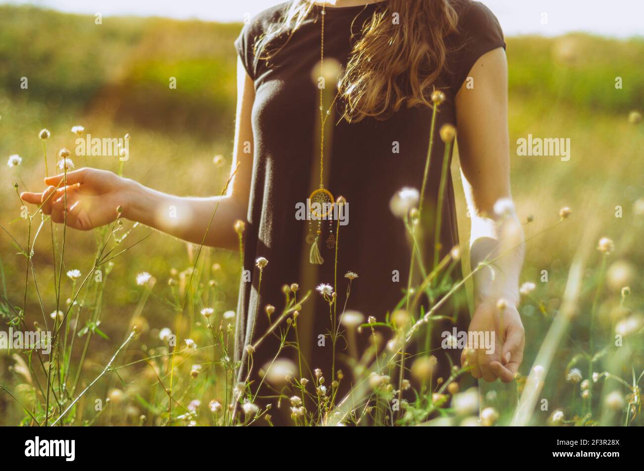 Mittelteil Porträt boho Stil Kleid junge Frau zu Fuß im Gras und Wildblumen mit der Natur verbinden. Konzept: Spiritualität, Zen, Balance Stockfoto