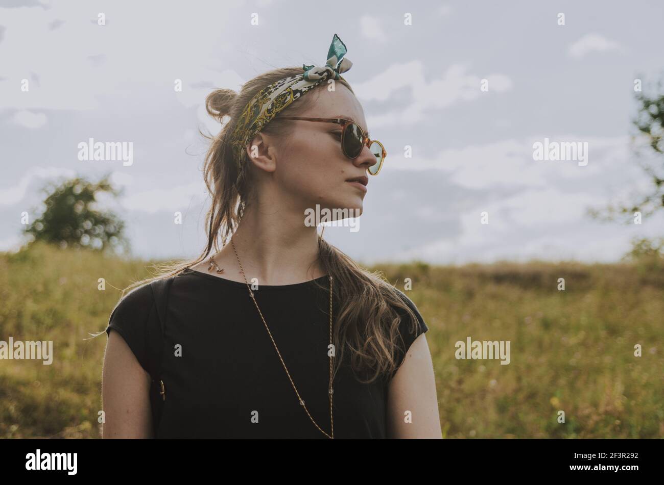 Oberes Porträt einer Frau mit einem Stirnband und einer Sonnenbrille, die zur Seite schaut Stockfoto