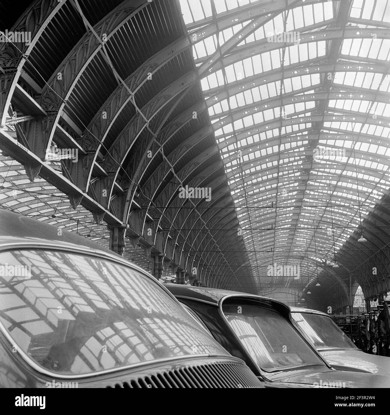 PADDINGTON STATION, London. Innenansicht mit dem Dach des Bahnhofs Paddington, spiegelt sich in den Fenstern der geparkten Autos wider. John Gay. Datum des Erläuschens Stockfoto