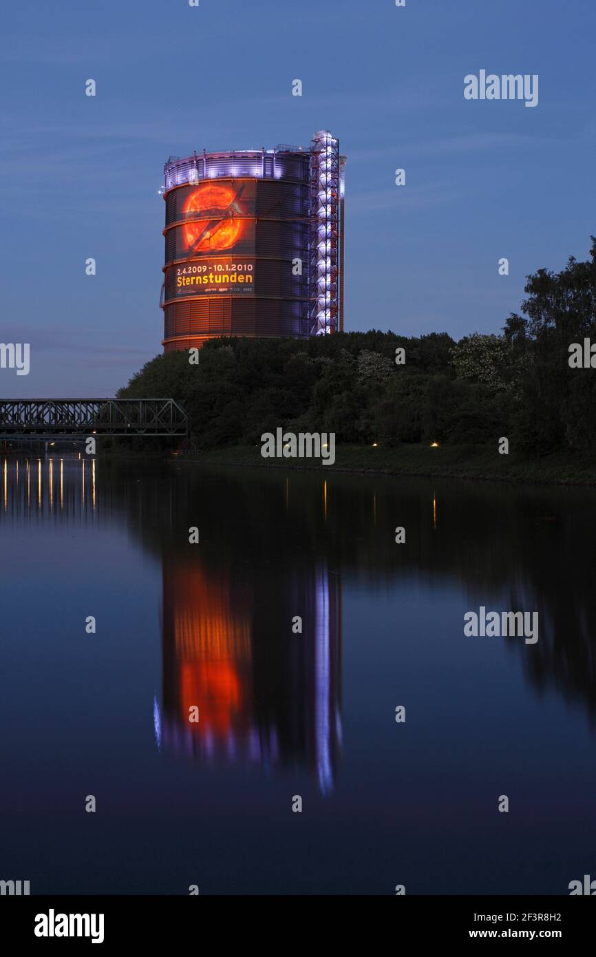 Blick auf den Rhein-Herne-Kanal bei Nacht zum beleuchteten Oberhausen Gasometer, Oberhausen, Deutschland. Stockfoto