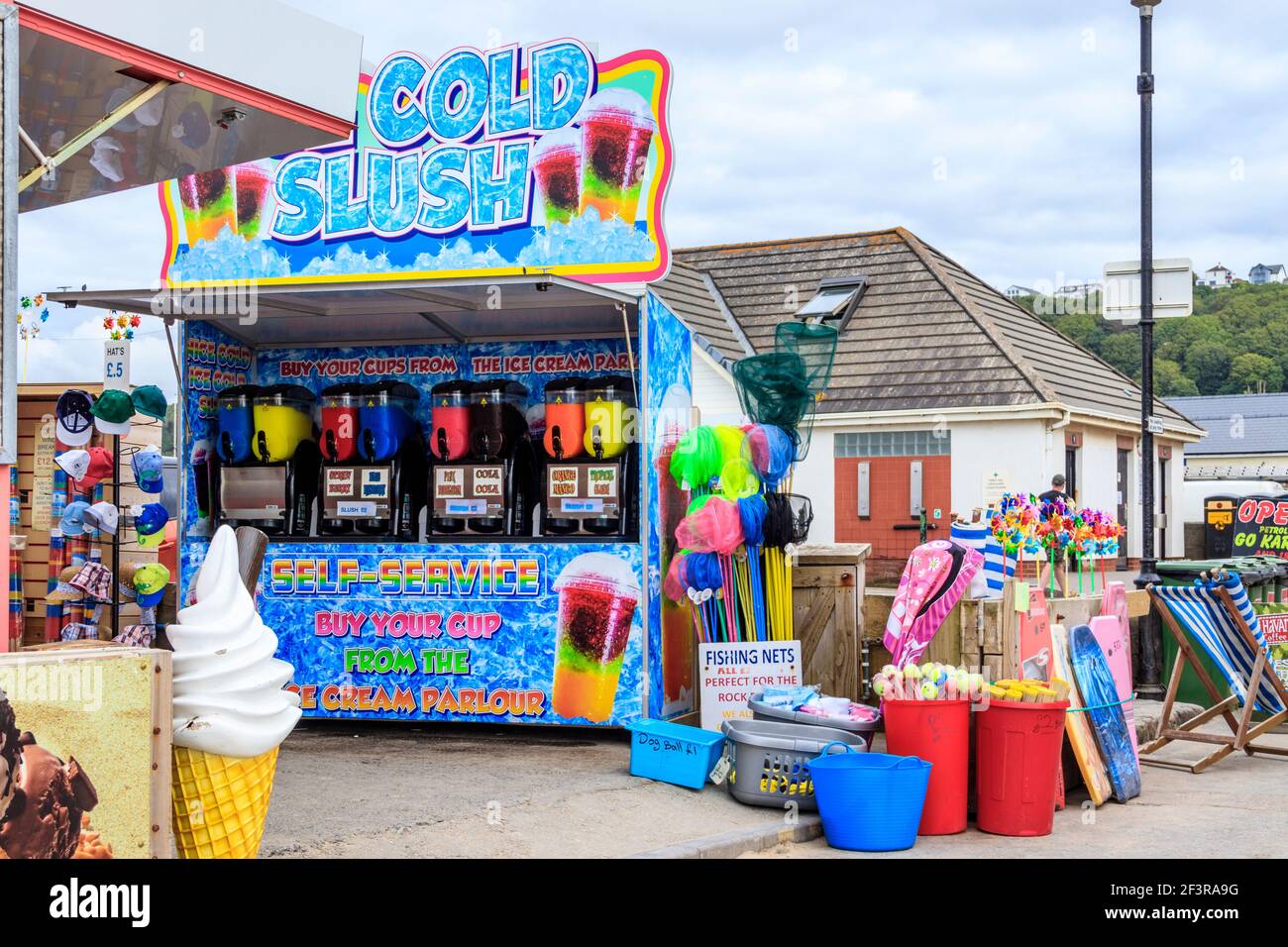 Ein Stall, der eiskalten Slush an der Küste serviert, sowie Fischernetze und andere Strandspielzeug, Westward Ho!, Devon, UK Stockfoto