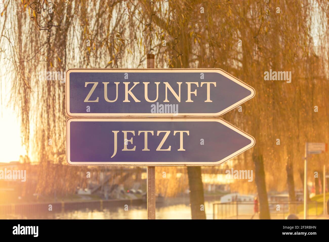 Zwei Schilder, die in die gleiche Richtung mit dem Deutschen zeigen Worte für die Zukunft und das Jetzt Stockfoto
