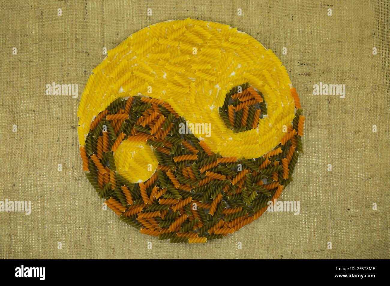 Das Konzept von Yin Yang. Zeichen Yin Yang vor dem Hintergrund der Sackleinen. Es wurde farbige Pasta mit natürlichen Farbstoffen verwendet. Stockfoto