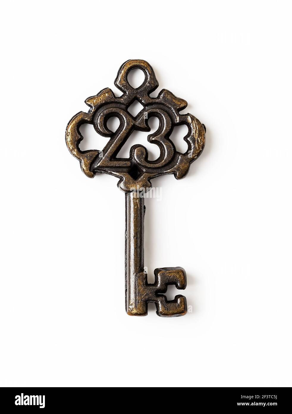 Makro-Aufnahme von kleinen Vintage-Schlüssel mit der Nummer 23 darauf isoliert auf weißem Hintergrund. Retro Shabby Brown Metallschlüssel Nahaufnahme. Altmodisches Design-Element Stockfoto