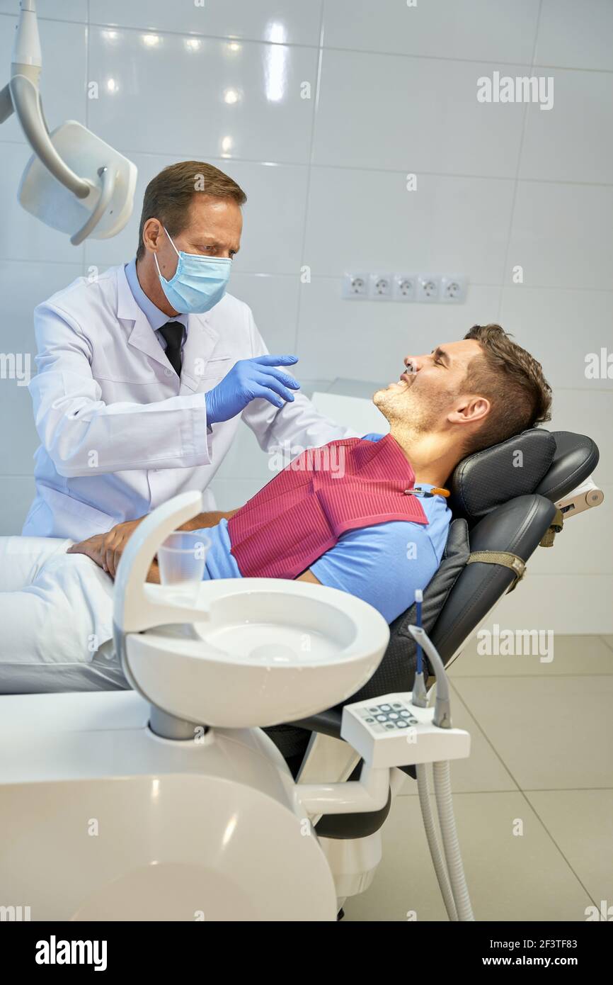 Professioneller Zahnchirurg, der einen medizinischen Check-up für einen jungen Mann durchführt Stockfoto