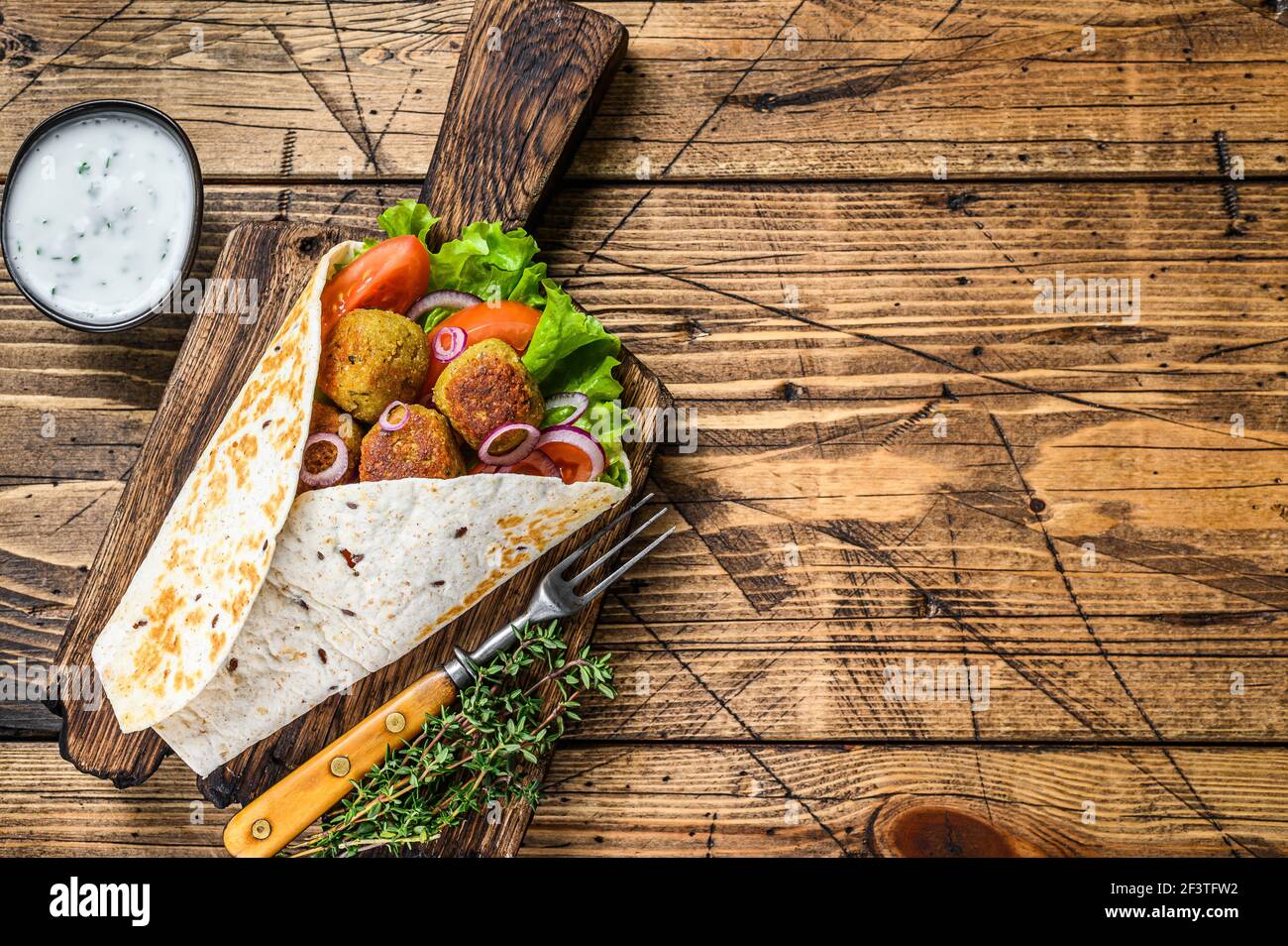 Vegetarische Tortilla Wrap mit Falafel und frischem Salat, vegane Tacos. Holzhintergrund. Draufsicht. Speicherplatz kopieren Stockfoto