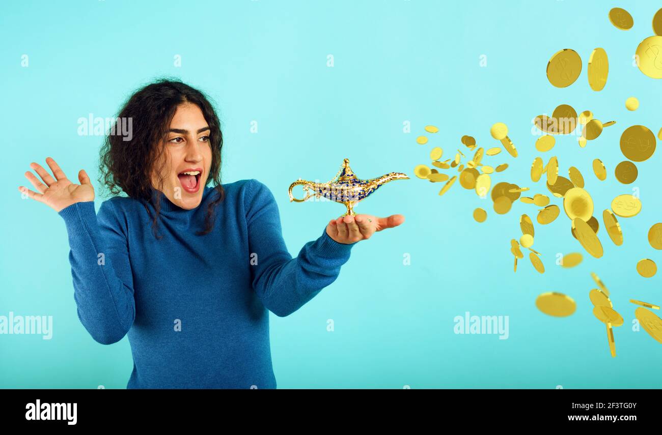 Frau ist glücklich, weil sie Lampe von aladdin gründet und um Geld bittet. Cyanfarbener Hintergrund Stockfoto