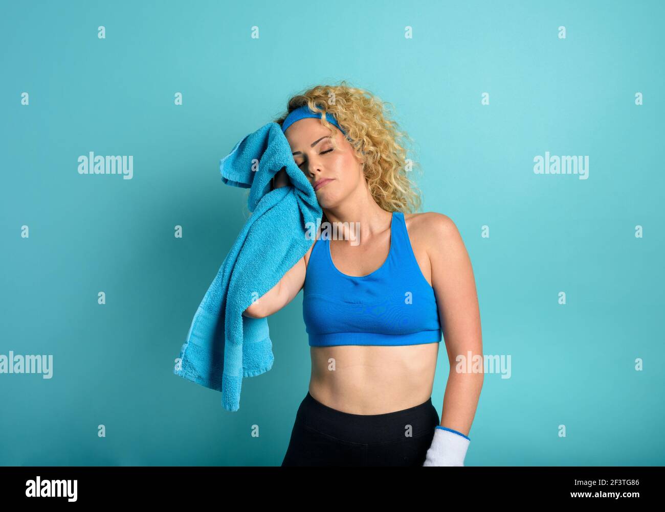 Frau tut Gym zu Hause. Müde Ausdruck. Cyan Hintergrund Stockfoto
