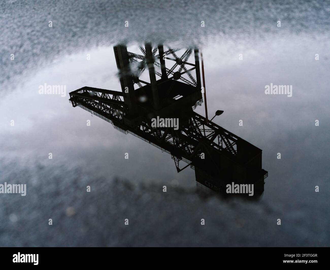 Alternative Ansicht des ehemaligen Clydeside Schiffbaus Finnieston Crane, bekannt als Titan, reflektiert in Pfützen in der Dämmerung, Glasgow, Schottland. Stockfoto