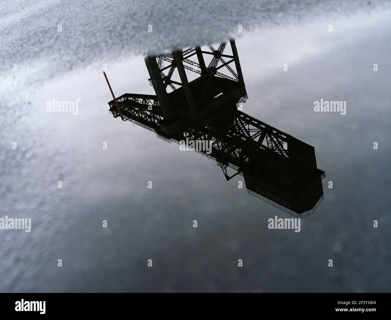 Alternative Ansicht des ehemaligen Clydeside Schiffbaus Finnieston Crane, bekannt als Titan, reflektiert in Pfützen in der Dämmerung, Glasgow, Schottland. Stockfoto