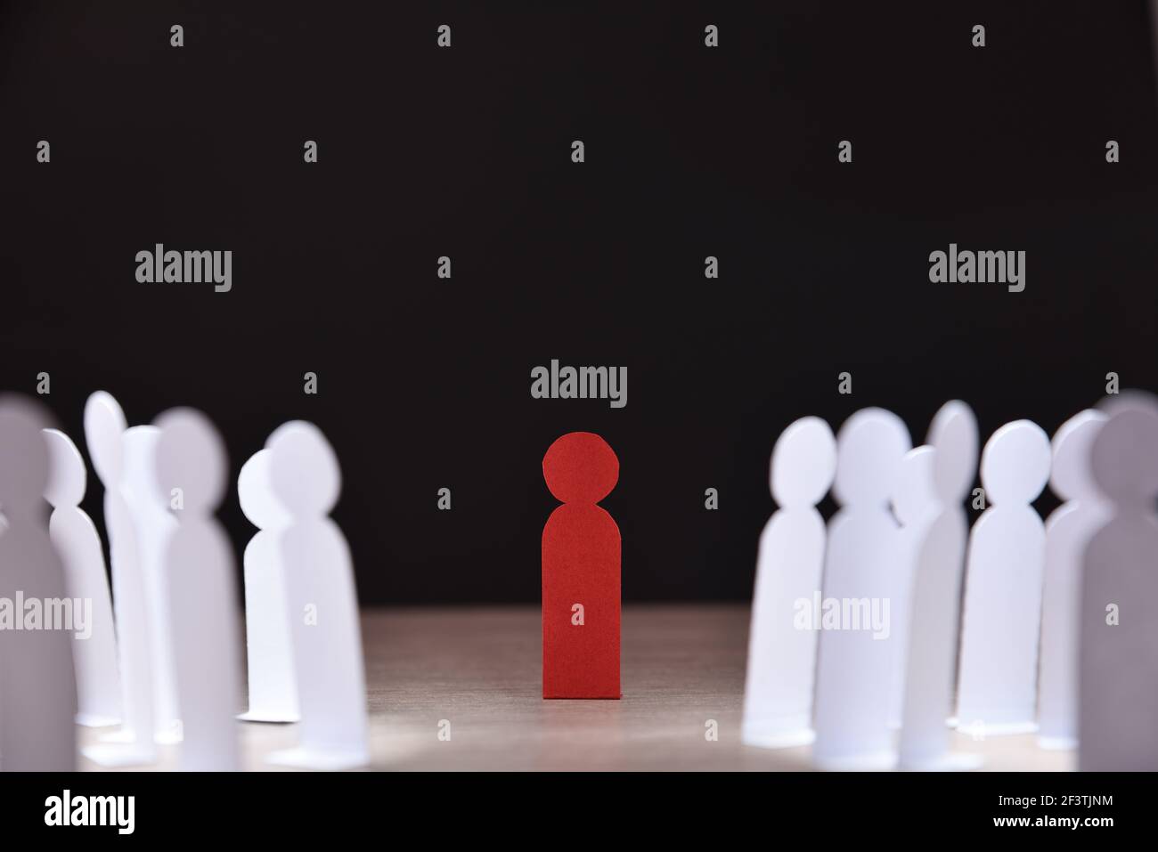 Soziale Diskriminierung Konzept mit vielen kleinen weißen Papier Männer um Eine andere auf Holzsockel und dunklen Hintergrund vorne Anzeigen Stockfoto