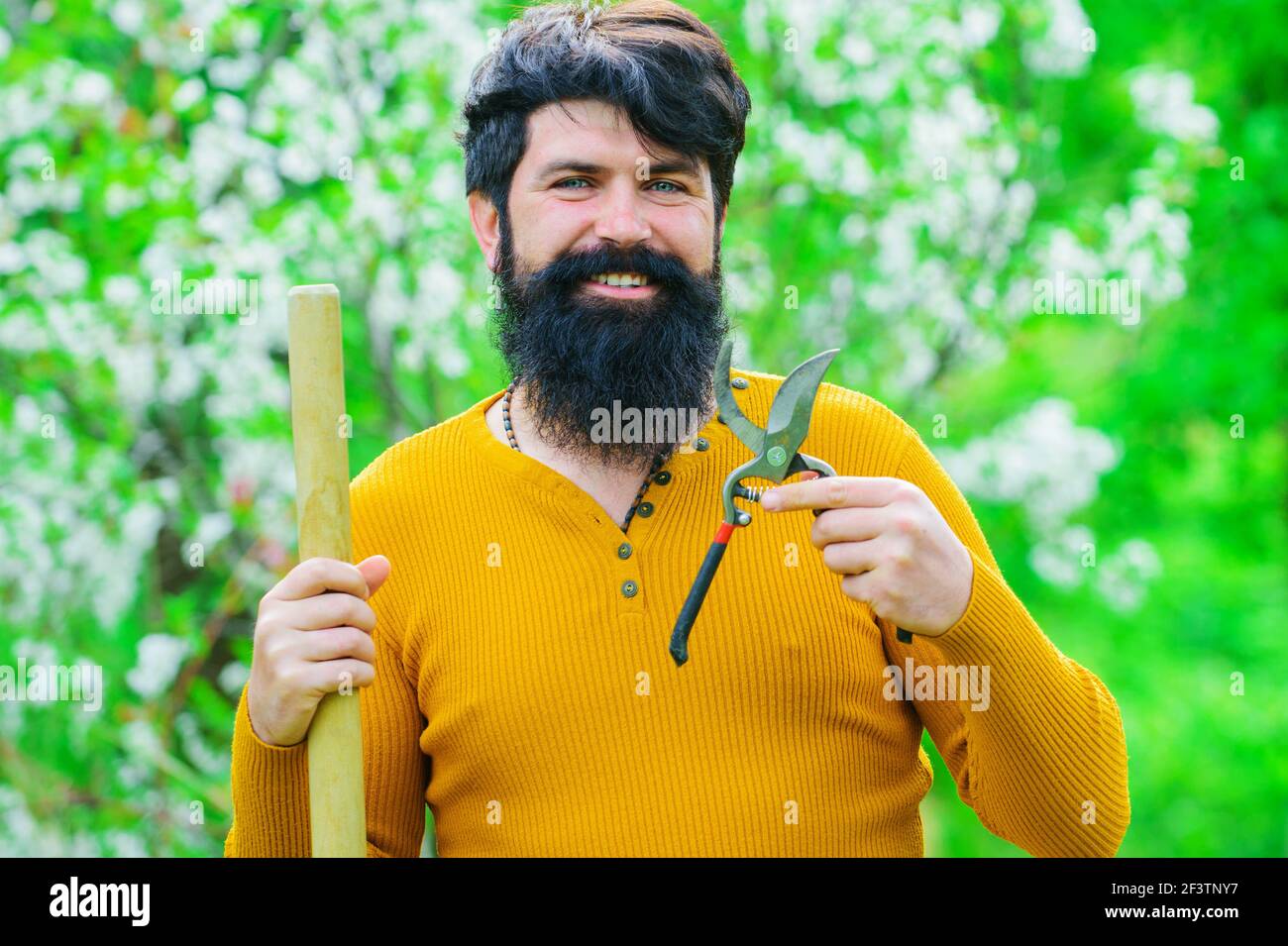 Lächelnder Mann mit Gartenschere. Gartenarbeit im Frühling. Stockfoto