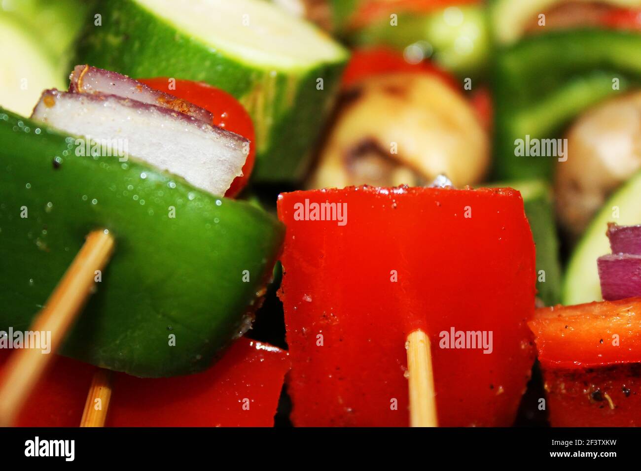 Nahaufnahme von rohen Gemüsespießen, mit grünem Pfeffer, rotem Pfeffer, Zucchini, Pilzen, Rote Zwiebel, Kirschtomate und Gewürze. Stockfoto