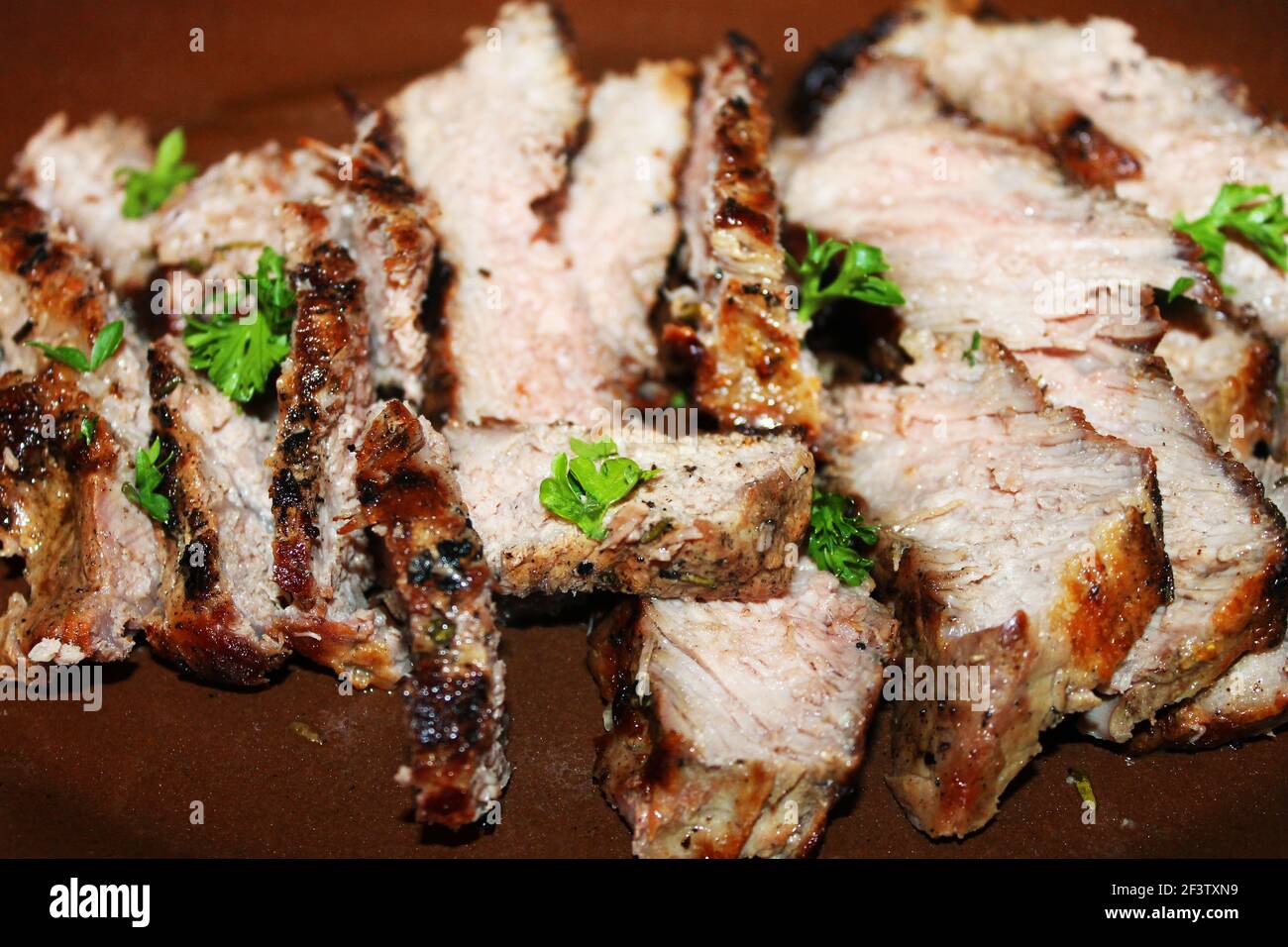 Nahaufnahme von in Scheiben gebackenem Schweinefleisch auf einem Servierteller. Stockfoto