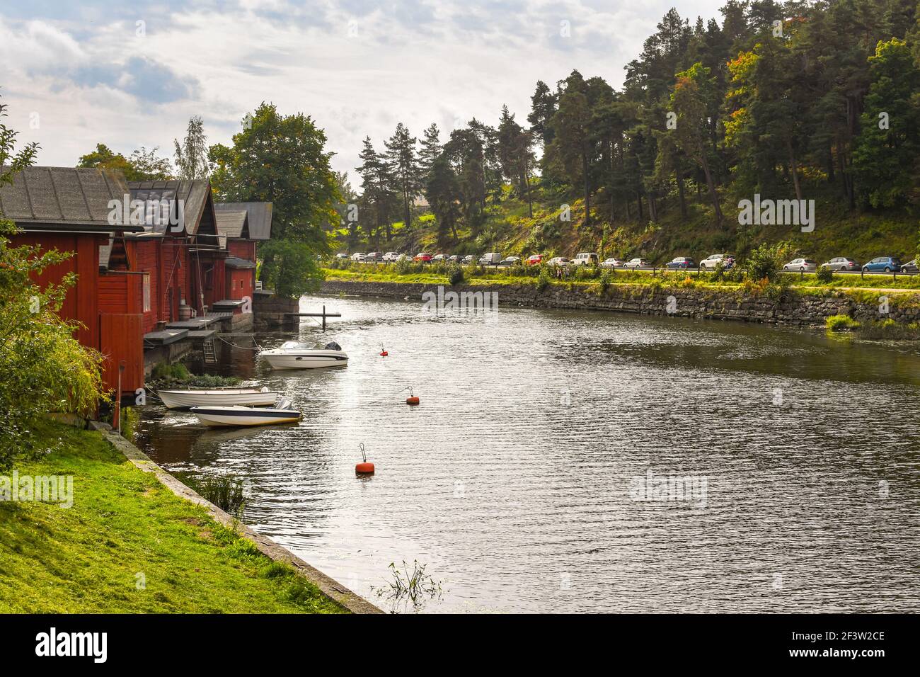 An einem ruhigen Sommertag im mittelalterlichen Dorf Porvoo, Finnland, säumen Häuser am Wasser mit Bootsanlegestellen den Fluss Porvoonjoki. Stockfoto