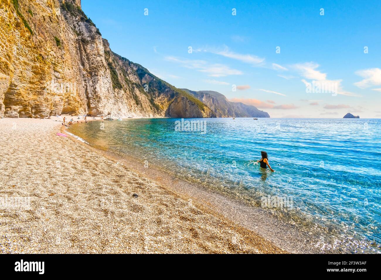 Eine Frau wagt im türkisblauen grünen Meer vor dem abgeschiedenen Paradies, oder Chomi Beach auf der Insel Korfu, Griechenland. Stockfoto