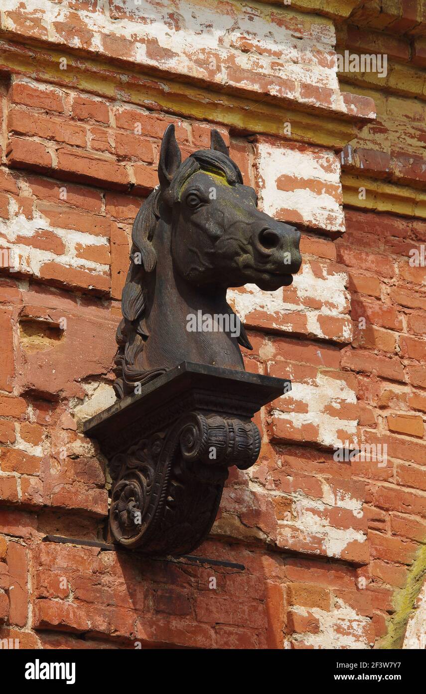 Skulptur des Pferdekopfes auf der Ziegelmauer eines verlassenen Gestüts aus dem 19th. Jahrhundert (Pskow Oblast, Russland) Stockfoto