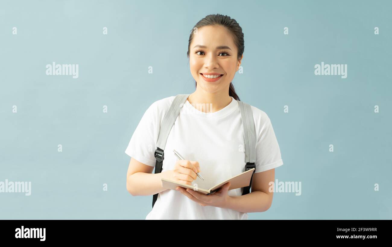 Nahaufnahme Foto schöne Frau gilt Rucksack aufmerksam Notizen schreiben Isolierter blauer Hintergrund Stockfoto