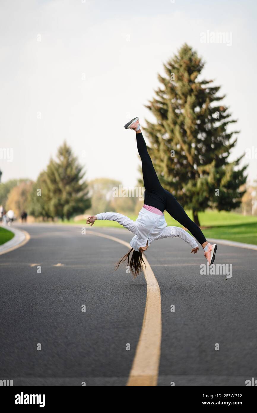 Frau Sportlerin springt auf die Straße und macht Übungen im Freien. Stockfoto