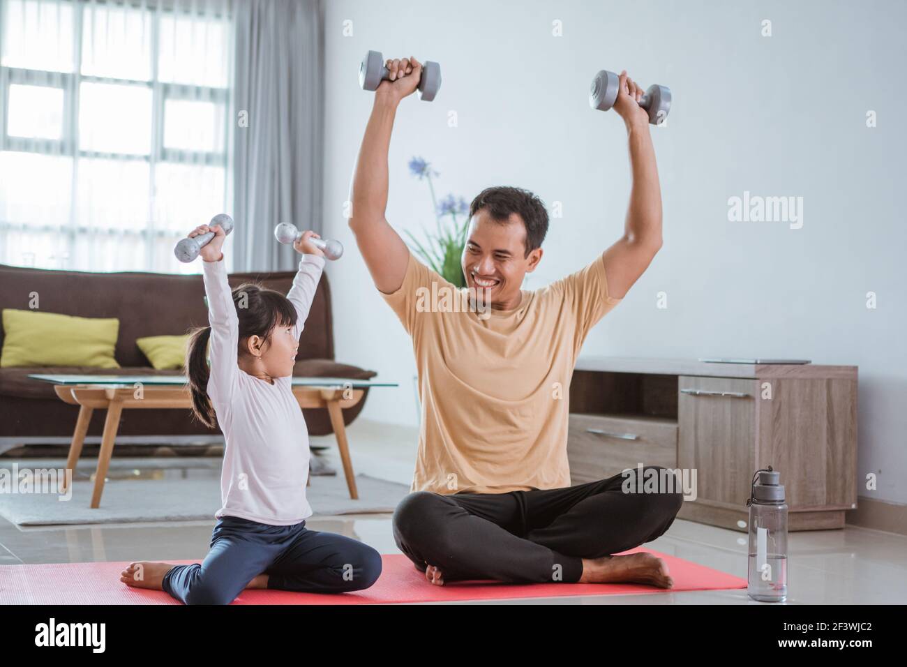 Glücklicher Vater und Tochter trainieren dabei Hantel heben zusammen Stockfoto
