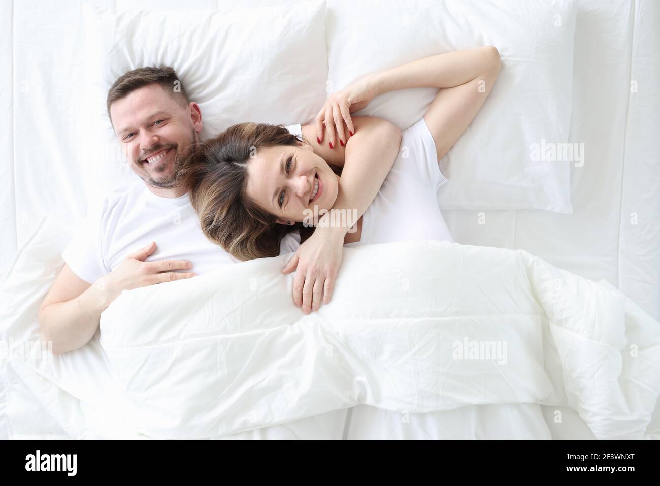 Lächelnd und glücklich liegen Mann und Frau in einer Umarmung Auf dem Bett  Stockfotografie - Alamy