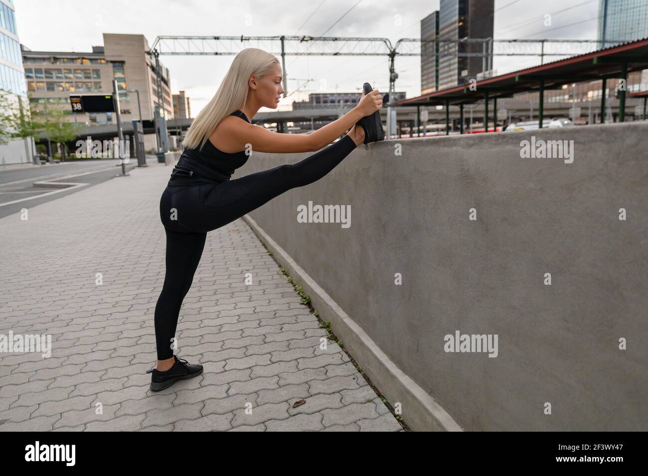 Fokussierte Junge Frau Streckt Bein Auf Geländer In Der Stadt Stockfoto