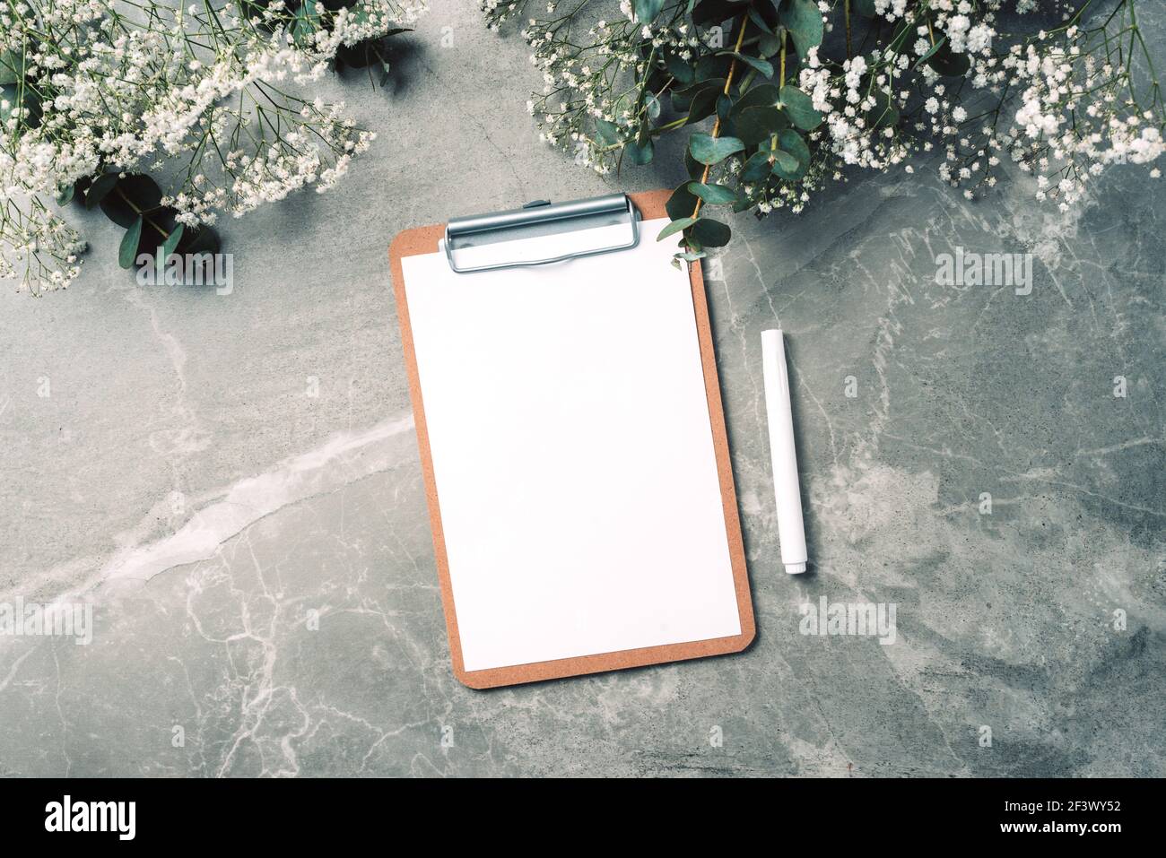 Femininer Arbeitsplatz mit Notizbuch, Klemmbrett, Papier, pinkfarbenem Pfingstrosen, Eukalyptusblüte auf Marmorboden. Draufsicht, Kopierbereich. Bloggerin, feminin Stockfoto