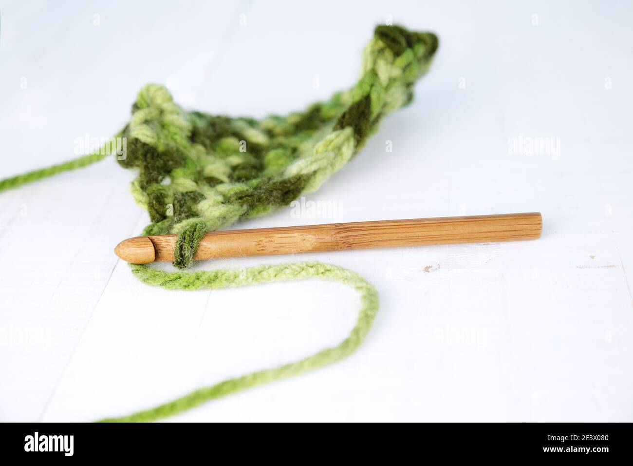 Häkeln mit grüner Wolle und Holz Natur Bambus Haken Stockfoto