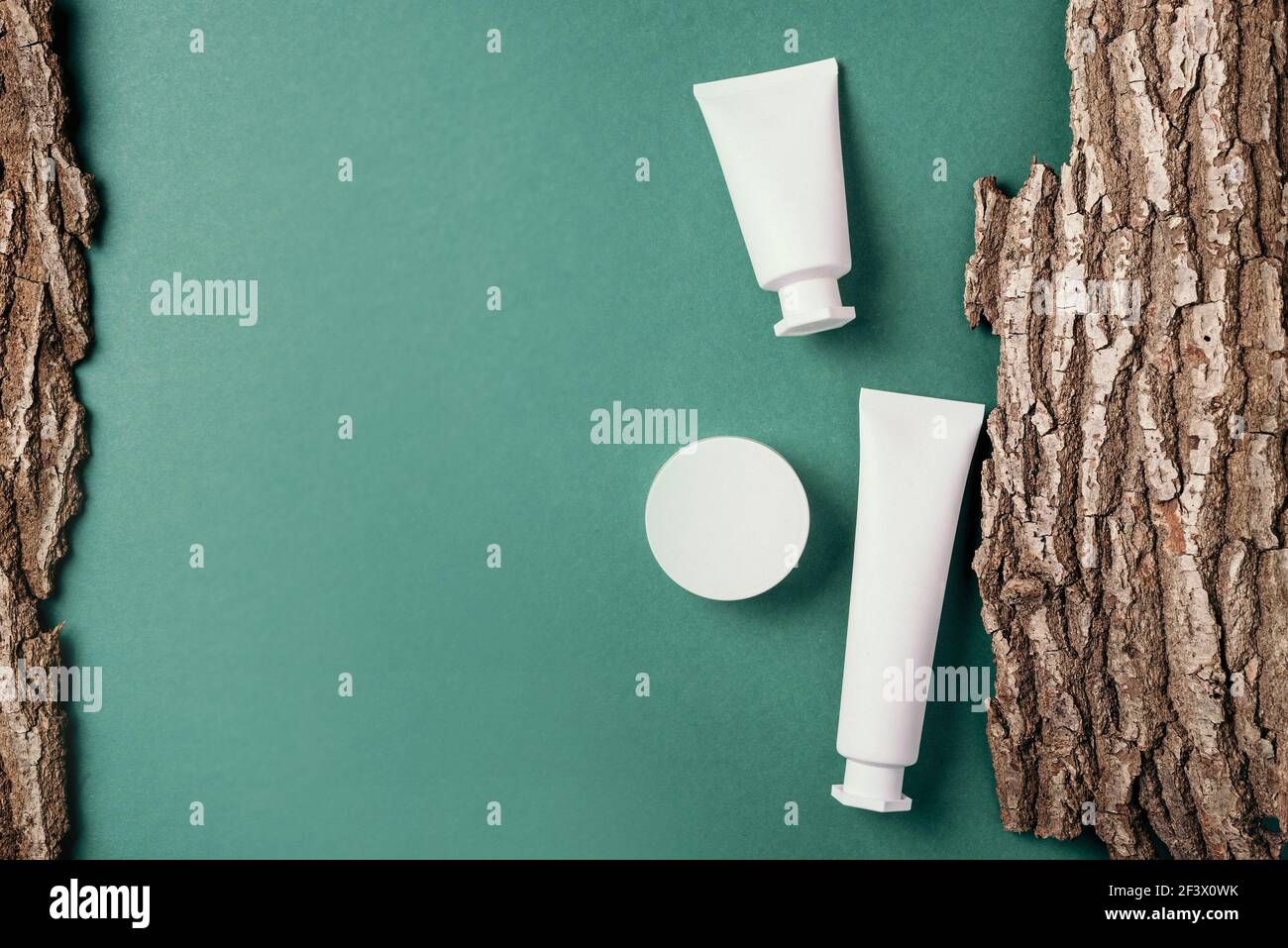 Weiße, unbeschriftete Kosmetikflasche auf trockenem Hintergrund aus Holzrinde. Hautpflege, organische Körperbehandlung, Hauternährungskonzept. Umweltfreundliches Produkt Stockfoto