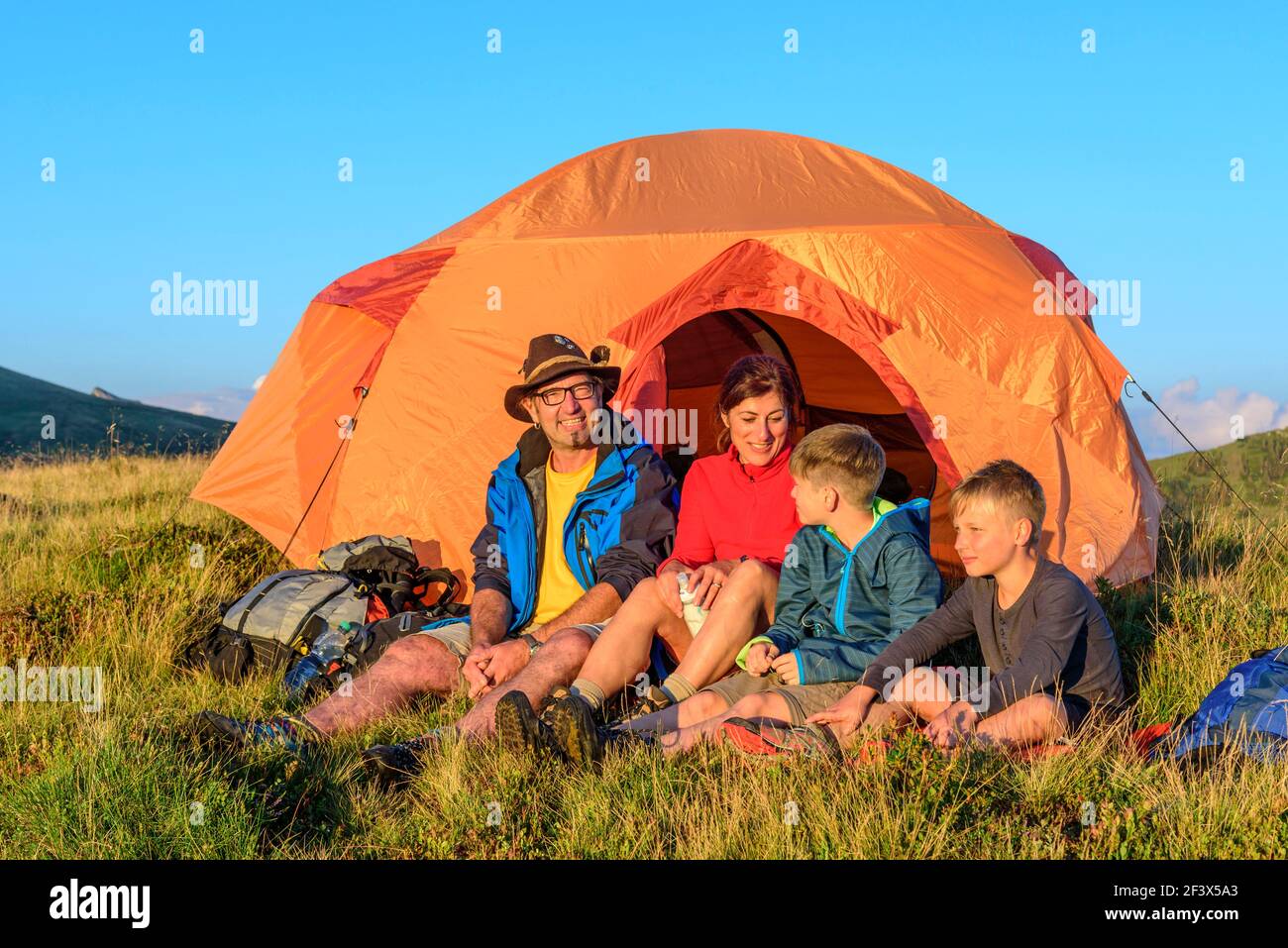 Familie genießt die Abendsonne vor einem Zelt Stockfoto